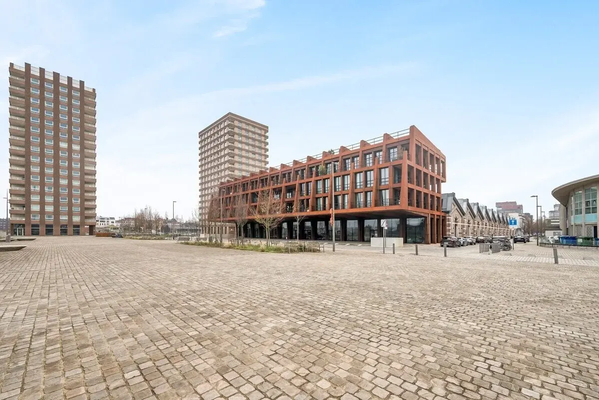 Modernes Apartmenthaus mit rostfarbener Stahlfassade an einem gepflasterten Platz in Antwerpen